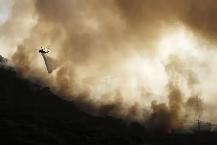 Framed Print : A firefighting helicopter drops water over a forest fire near Keratea