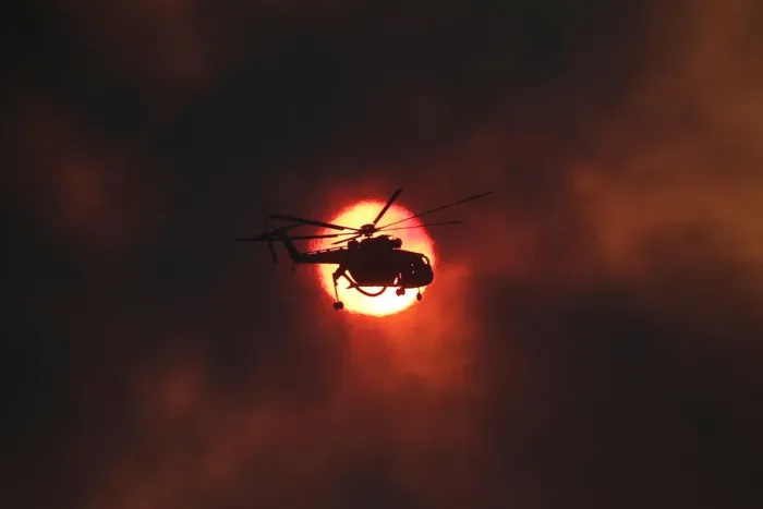 Framed Print : A firefighting helicopter flies in front of the setting sun as a wildfire burns near Framed Print : A firefighting helicopter flies in front of the setting sun as a wildfire burns near