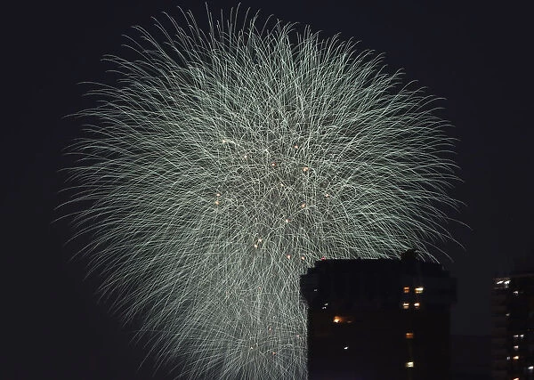 Fireworks explode over high-rise buildings during the Sumida River Fireworks Festival