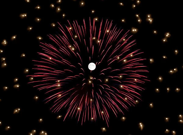 Fireworks explode in front of the full moon during celebrations marking the feast of the