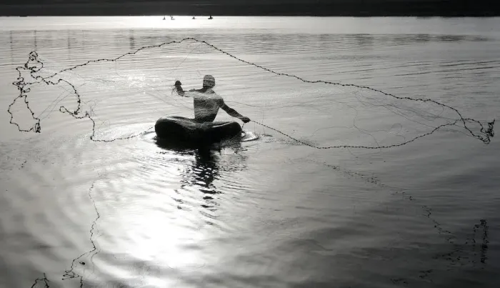 Framed Print : Fisherman floating on a rubber tube throws a net to catch fish from the waters of Framed Print : Fisherman floating on a rubber tube throws a net to catch fish from the waters of