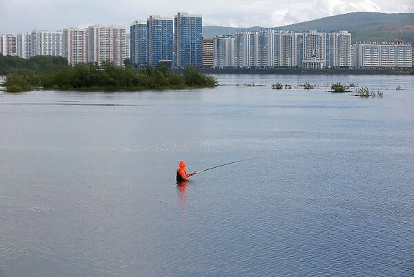 A fisherman stands in the waters of the Yenisei River in the Siberian city of Krasnoyarsk