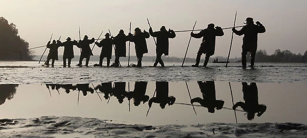 Fishermen pull a net containing fish from a lake at the village of Bosilec during