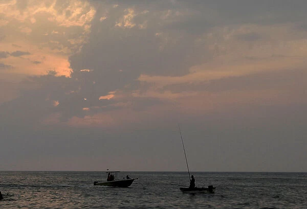 Fishermen are seen fishing at the sea side during sunset in Beirut