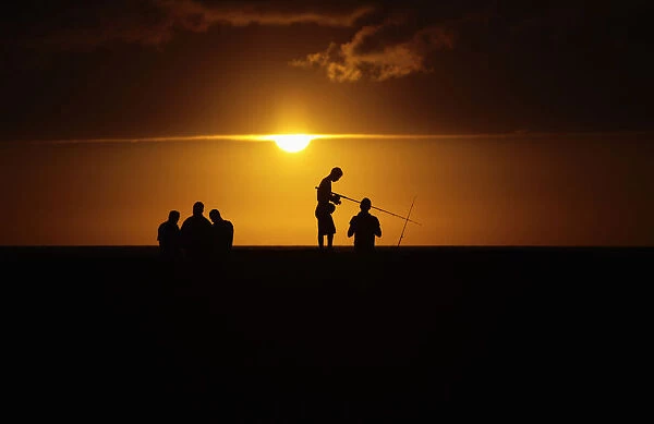 Fishermen stand on Havanas seafront boulevard El Malecon as the sun sets