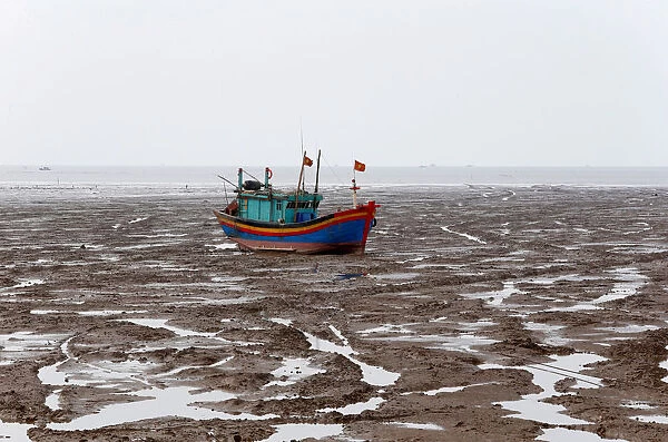 A fishing boat is seen during the low tide at the beach in Thanh Hoa province