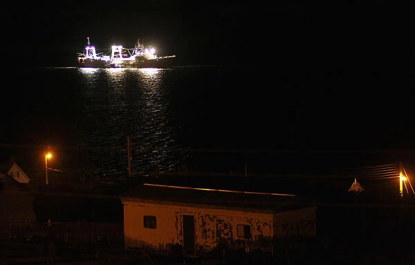 A fishing ship is seen at night along the coast of Port Stanley