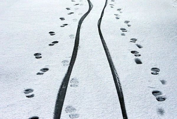 Footprints and cycle tracks are seen on a snowy road in Buxton