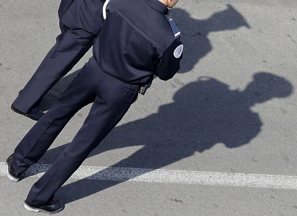 French policemen cast their shadows on the pavement as they stand guard near the Festival