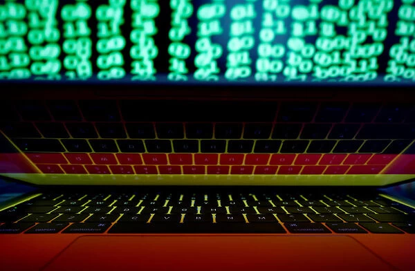 German flag is seen on the laptop screen in front of a computer screen on which cyber