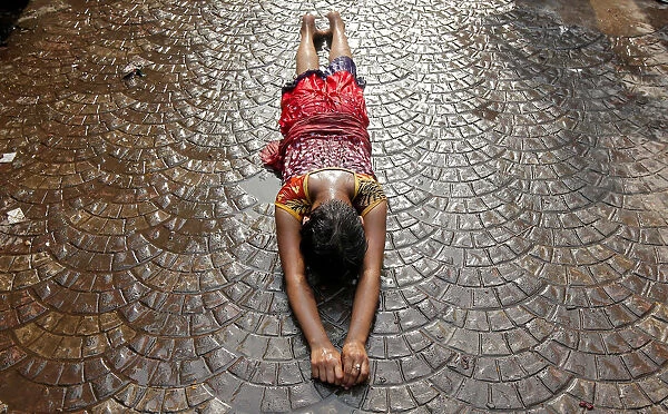 A girl lies on a road as she performs a ritual while worshipping Sheetala Mata