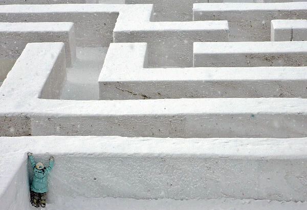 A girl tries to climb a snow-packed wall in a labyrinth at the Sapporo Snow Festival
