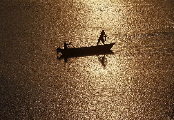 Girls are silhouetted against the rising sun as they fish in the waters of the Ganges