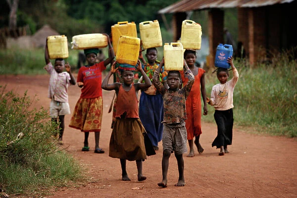GM1E52K064V01. Children carry containers of water in the village of Bangadi