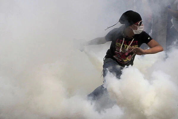 GM1E8BR1O7Q01. An anti-Mursi protester runs to throw a tear gas canister