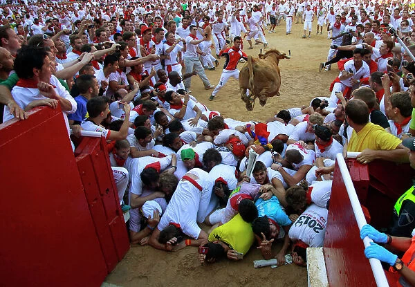 GM1E9771BBT01. A fighting cow leaps over revellers upon entering the bullring