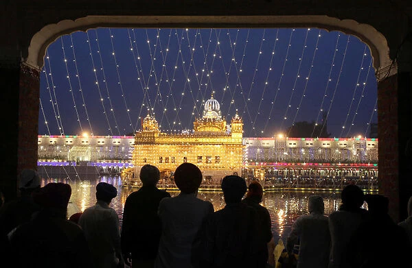 The Golden Temple is seen illuminated as Sikh devotees arrive on the eve of the 550th
