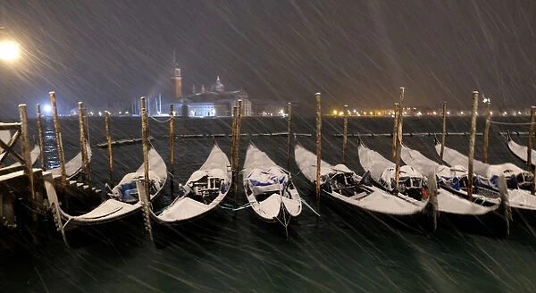 Gondolas are seen during snowfall in the Venice lagoon