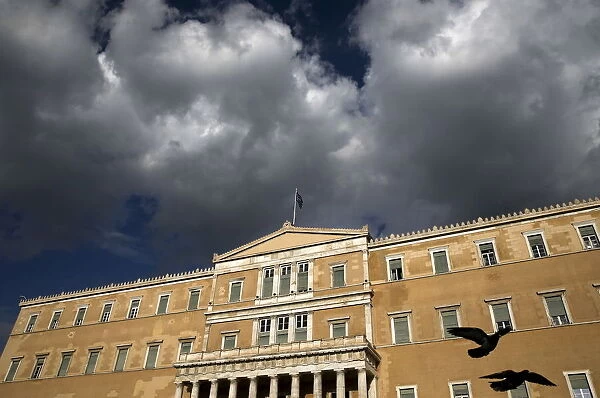A Greek national flag flutters atop the parliament building in Athens