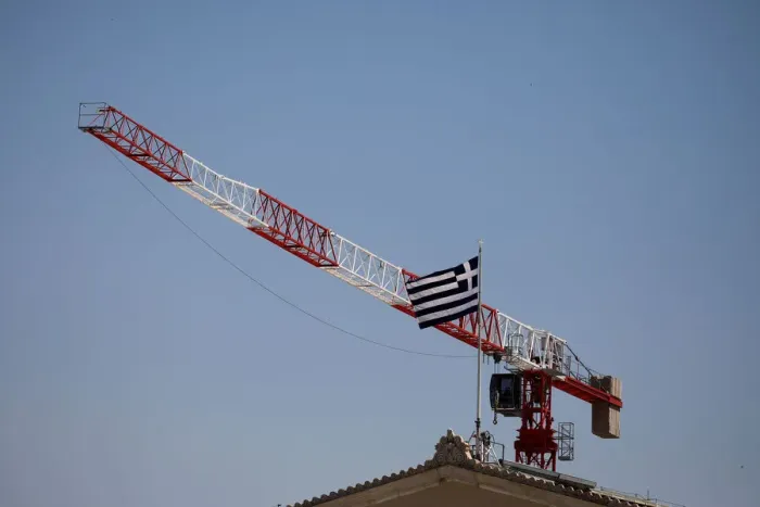 Framed Print : A Greek national flag flutters atop the parliament building as a construction crane is Framed Print : A Greek national flag flutters atop the parliament building as a construction crane is