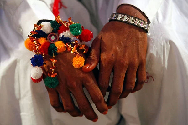 A groom wears a traditional handmade garland on his wrist