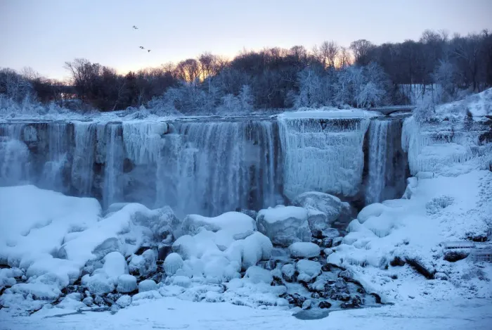 Framed Print : A group of birds fly past ice and water flowing over the American Falls