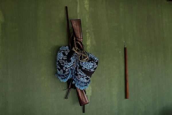 Guns hang with a hammock on the wall of a Tembe indigenous tribes house