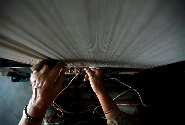A hand of a Tibetan refugee is pictured as she works to weave a traditional carpet