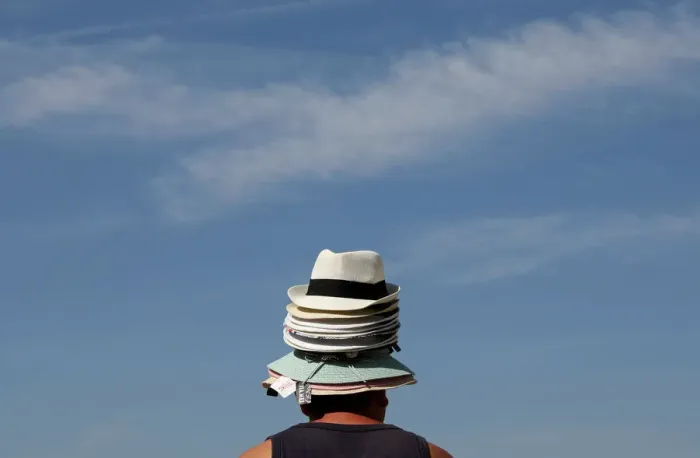 Framed Print : A hat seller wears his merchandise on his head as he tries to sell hats to tourists