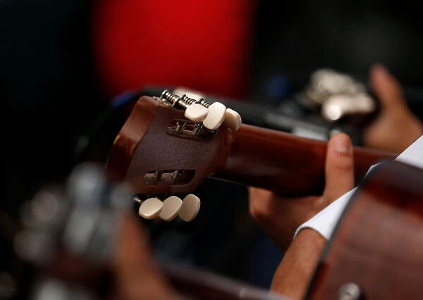 The headstock of a guitar is seen as folk music guitarists perform during the traditional