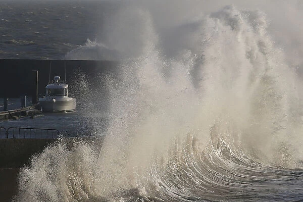 A high wave crashes on the protecting wall at the fishing harbour in Pornic