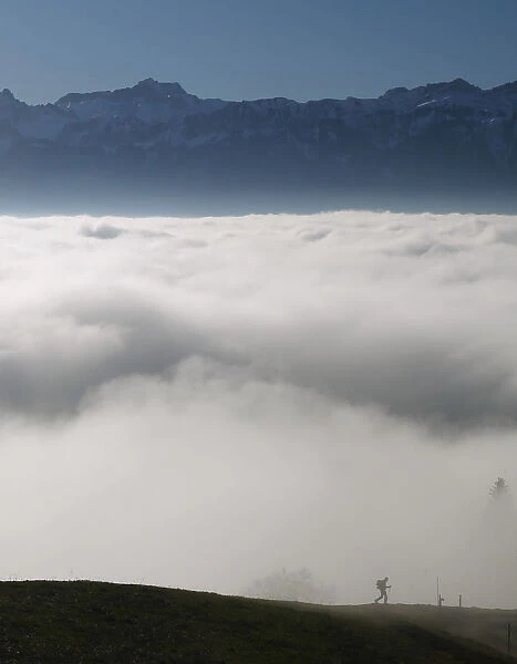 A hiker walks into a sea of fog over Lake Leman at the Tour de Gourze near Lausanne