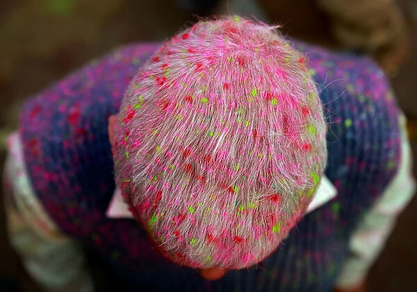 A Hindu devotee is covered in coloured powder as he stands outside a temple during the