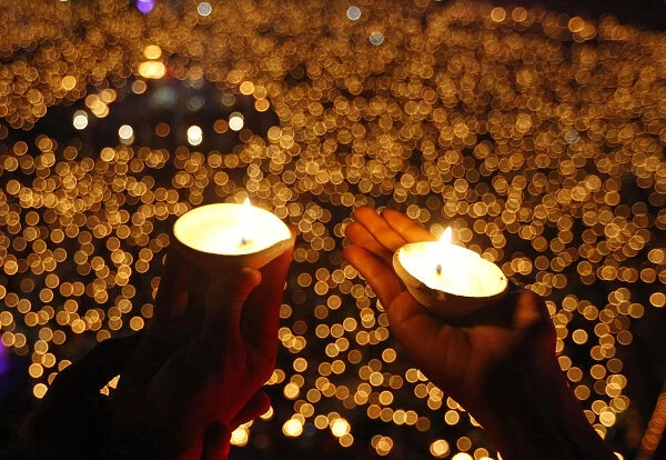 Hindu devotees hold earthen lamps to perform prayers called Aarti during the celebrations