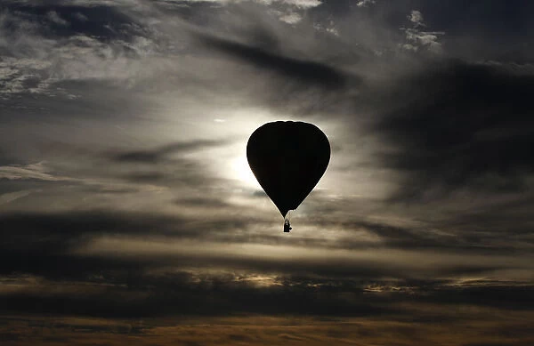 A hot air balloon is silhouetted at sunrise after taking off from Reconciliation Place