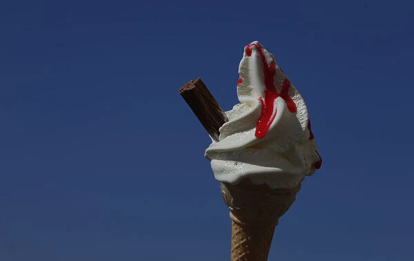 An ice cream cone is held against a blue sky in Blackpool