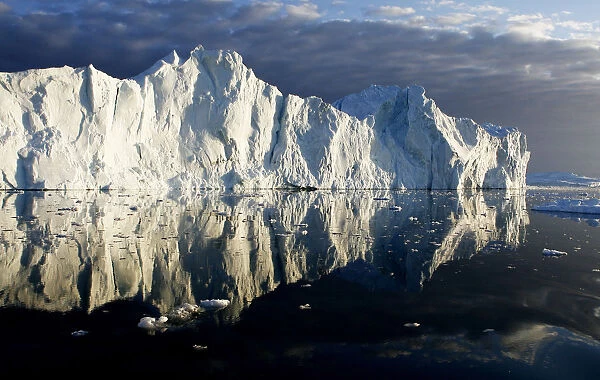 Icebergs are reflected in the calm waters at the mouth of the Jakobshavn ice fjord