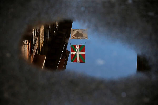 An Ikurrina and a banner that reads, Basque Prisoners to Basque Country, are reflected