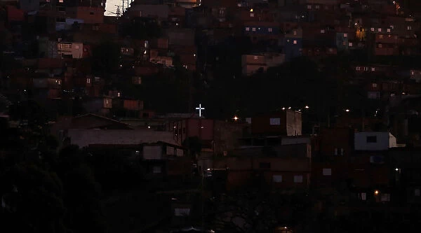 An illuminated cross is seen among houses in a slum in Sao Bernardo do Campo