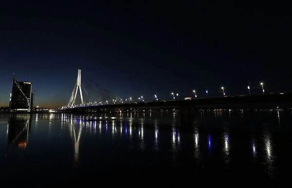 An illuminated suspension bridge over the Daugava river is pictured in Riga
