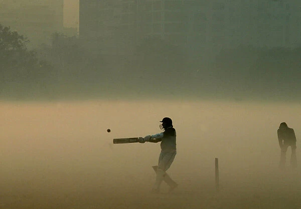 Indian boys play cricket amid thick fog during a chilly morning in Kolkata
