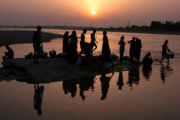 Indian labourers take a bath in the river Tawi in Jammu