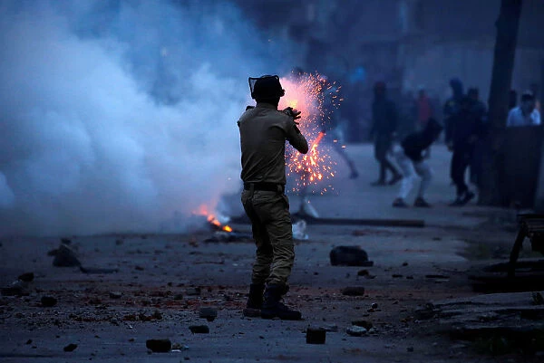 Indian police officer fires tear gas shell towards demonstrators in Srinagar