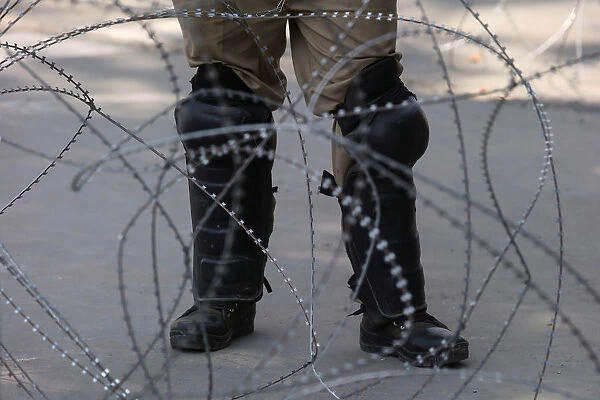 An Indian police officer stands behind the concertina wire during restrictions