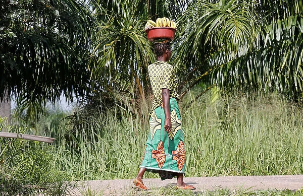 An internally displaced Congolese woman carries a basin containing bananas as she walks