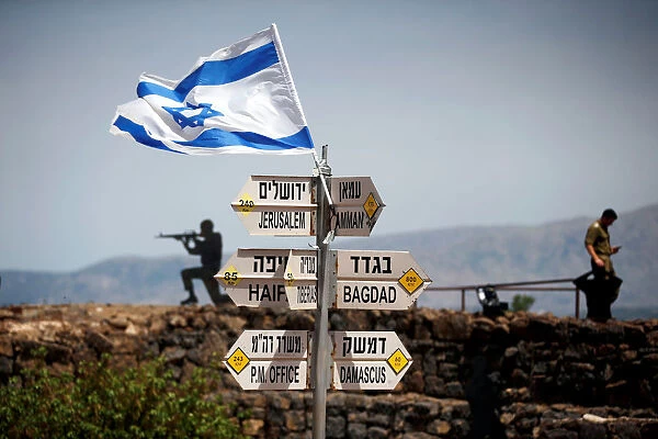 An Israeli soldier stands next to signs pointing out distances to different cities