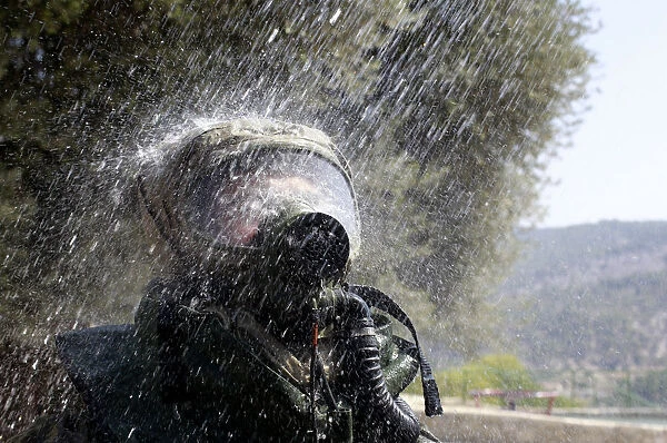 An Israeli soldier wearing a protective gear is sprayed with water during a drill