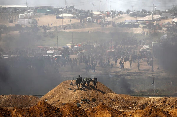 Israeli soldiers are seen next to the border fence on the Israeli side of the Israel-Gaza