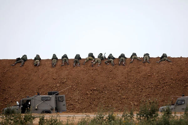Israeli soldiers are seen next to the border fence on the Israeli side of the border with