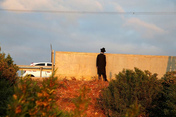 An Israeli ultra-Orthodox Jew looks over a wall as demonstrators block a road during a